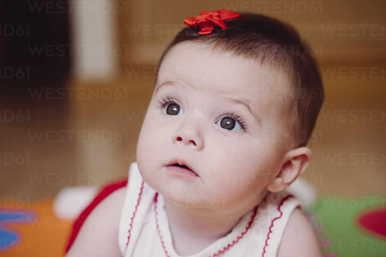 Close-up of cute baby girl with red hair clip looking away while ...